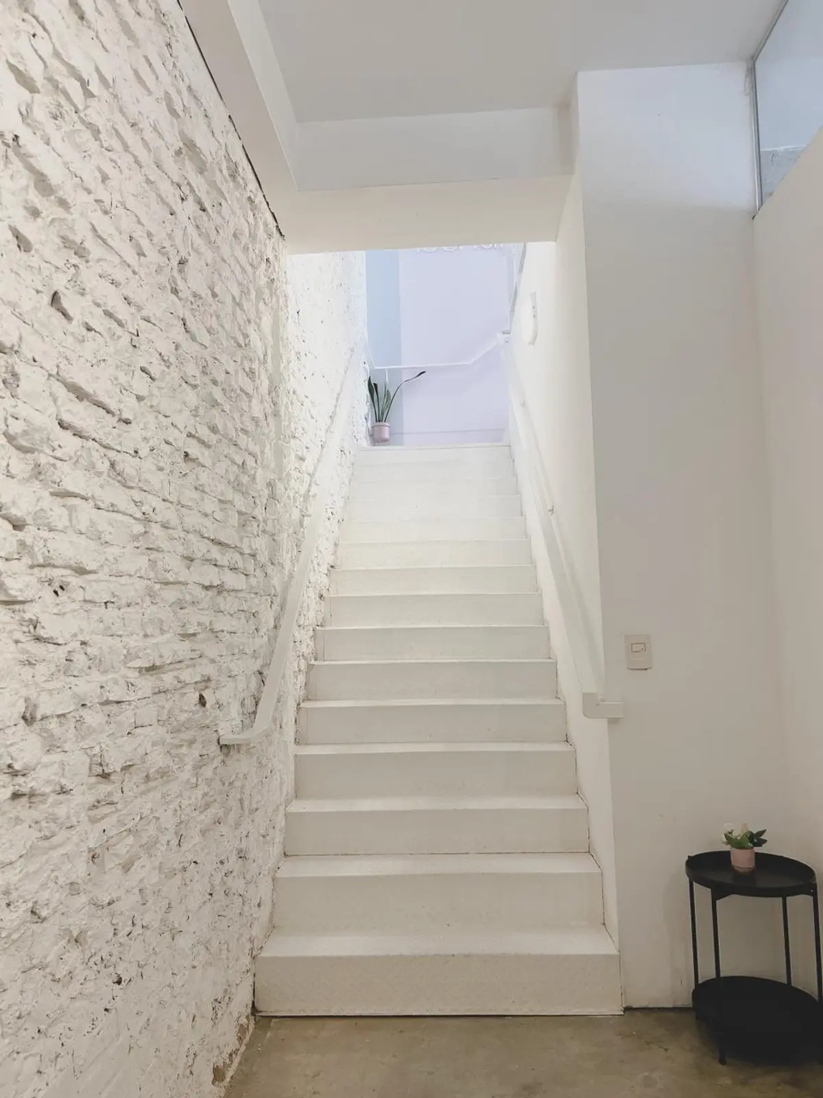 Escada minimalista com parede de tijolos brancos aparentes — projeto NAZZARRE | Oficinas, por dariorivero.estudio, em Buenos Aires